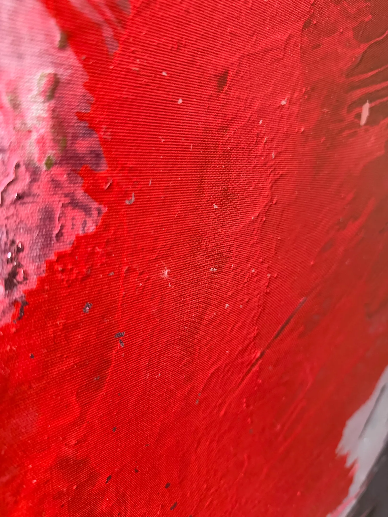 Detail of Genesis of Flame: a passage of red paint with the canvas weave visible, small ridges of paint and a pink passage at the left edge — Alyne Perfeito, Perfeito Studio